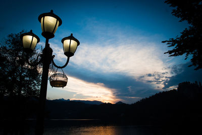 Low angle view of street light by lake against sky
