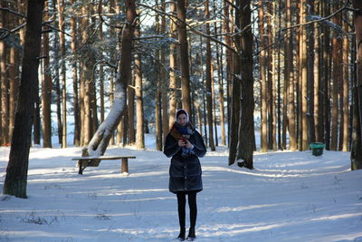 Portrait of woman standing on snowy field against trees