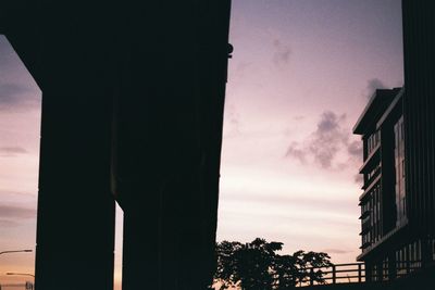 Low angle view of silhouette trees and building against sky