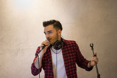 Portrait of young man standing against wall