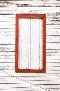 Closed red window on white wooden house