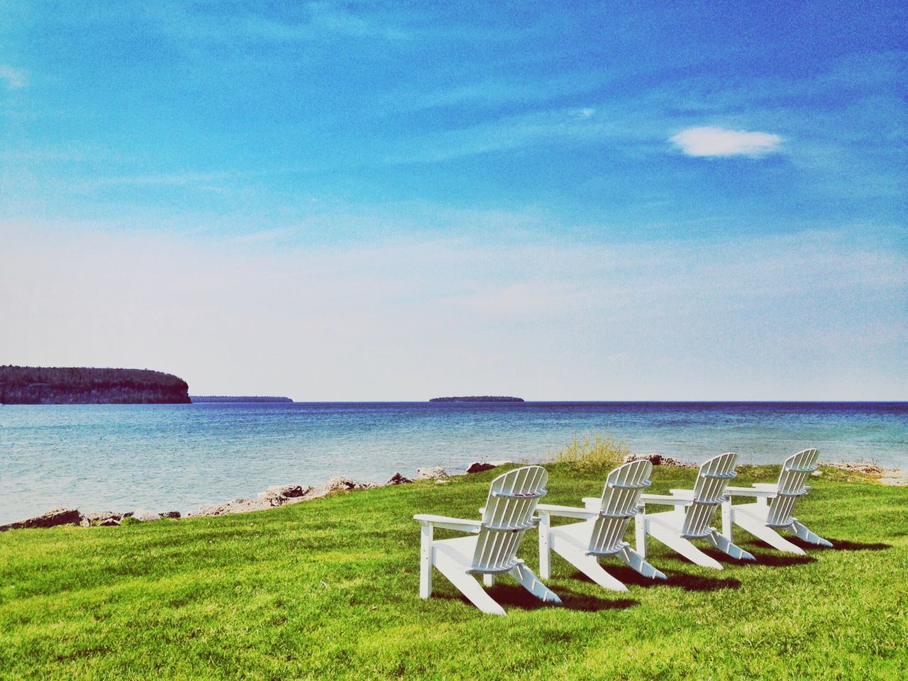 grass, sea, water, horizon over water, sky, tranquil scene, tranquility, scenics, blue, beach, nature, beauty in nature, green color, shore, day, idyllic, outdoors, relaxation, incidental people, vacations