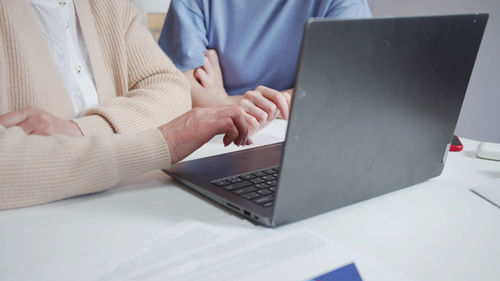 Midsection of woman using laptop on table