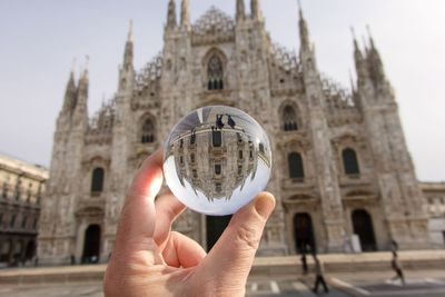 Close-up of hand holding crystal ball against milan cathedral 