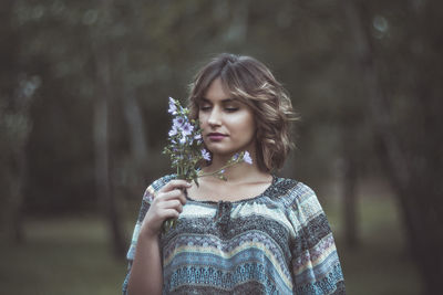 Close-up of beautiful woman standing against trees