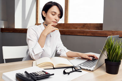 Woman using laptop while working at office