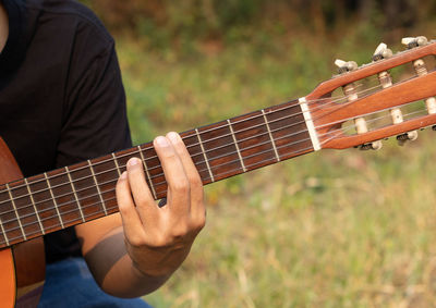 Midsection of man playing guitar