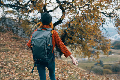 Rear view of man walking on street during autumn