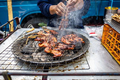 Cropped image of man preparing meat on barbecue grill