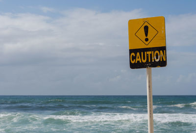 Information sign on beach against sky