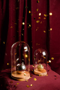 Glittering golden raining over shiny christmas bauble in glass dome placed on table at home for holiday