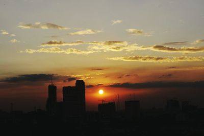 Silhouette cityscape against romantic sky at sunset