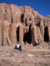 Rear view of man sitting on rock formations