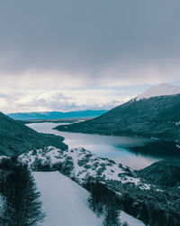 Scenic view of lake by snowcapped mountains against sky