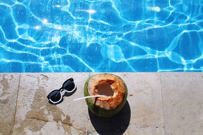 High angle view of sunglasses and coconut on swimming pool