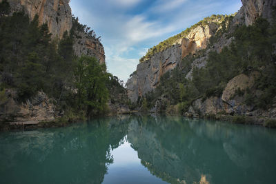 Scenic view of canal amidst mountains against sky