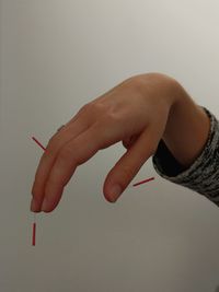 Close-up of hand holding cigarette against white background