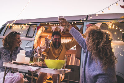 Mature friends toasting outside motor home during sunset