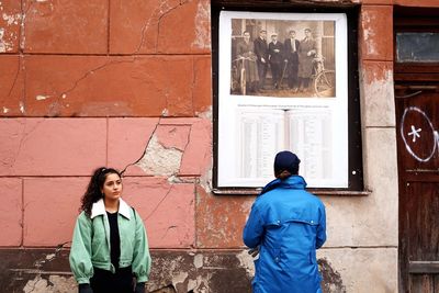 Portrait of young woman standing against brick wall