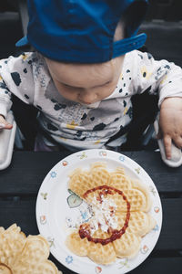 Directly above shot of girl having waffle at wooden table