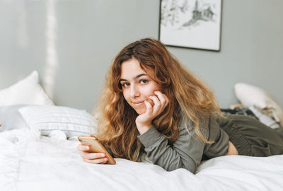 Portrait of woman lying on bed at home