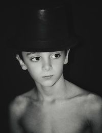 Portrait of shirtless boy against black background
