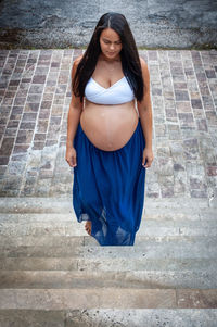 Beautiful latina girl in the last months of pregnancy with long black hair climbing a staircase