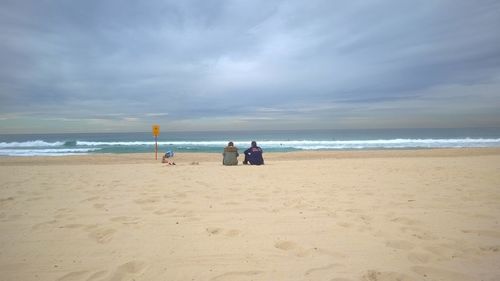 Rear view of people on beach against sky