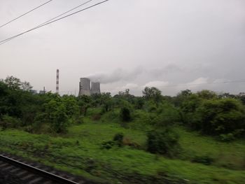 Trees by railroad tracks against sky