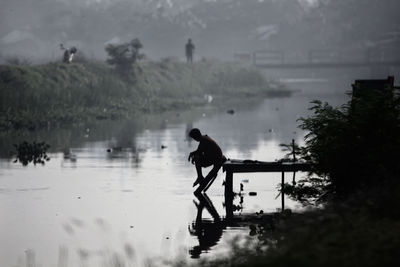 Side view of silhouette man standing by lake