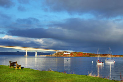 Bridge over sea against cloudy sky