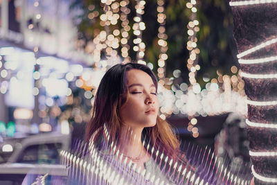 Close-up of young woman amidst illuminated lights