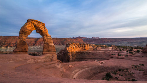 Rock formations on landscape against cloudy sky