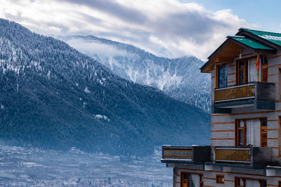 House on snowcapped mountain against sky