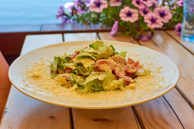 Caesar salad served in a white plate on a table