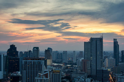 Modern buildings in city against sky during sunset