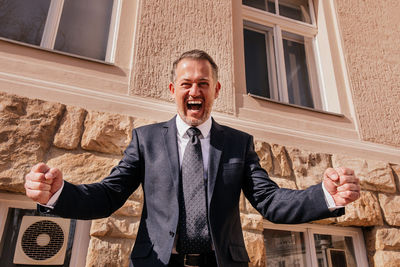 Business man in front of the office building, happy emotions, the end of the work day