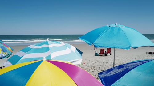 Colorful umbrellas on beach against clear blue sky