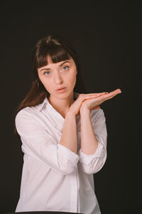 Portrait of woman standing against black background