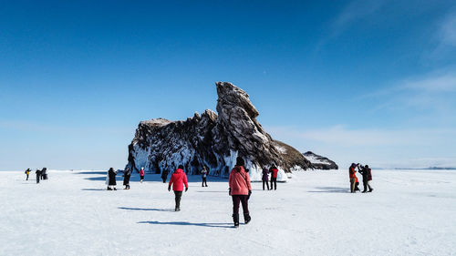 People on snow covered land against blue sky