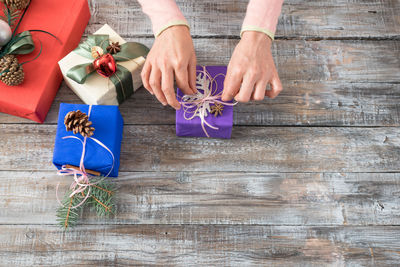 High angle view of woman preparing christmas gifts on wooden table