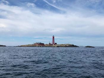 Lighthouse by sea against sky