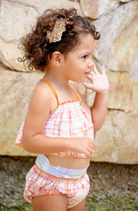 Cute girl looking away while standing against wall