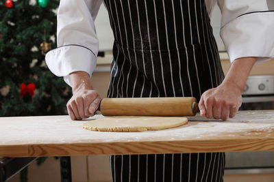 Midsection of chef rolling dough at table