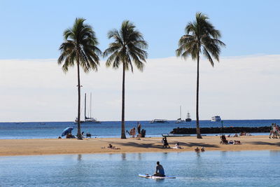 People enjoying at beach against sky