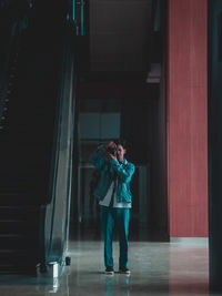 Full length of young man photographing from camera by escalator