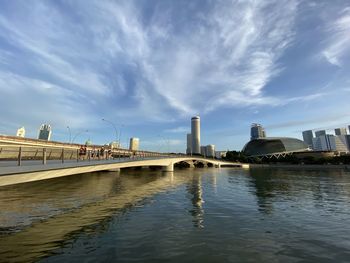 Bridge over river by buildings against sky