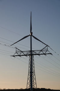 Low angle view of silhouette electricity pylon against sky during sunset