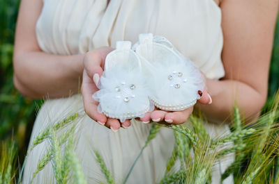 Close-up of woman holding white flower on field