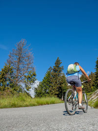 Rear view of man riding bicycle on road